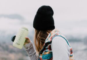 woman holding a bottle of water looking at mountains in the background