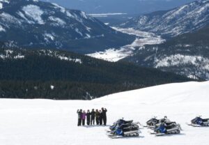 people standing in the snow with the mountains and a valley in the background