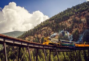 train on a raised bridge with fall trees in the background in Georgetown, CO