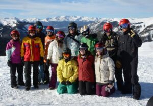 group of people wearing snow gear posed with mountains in the background