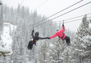 two people holding hands while ziplining in snow